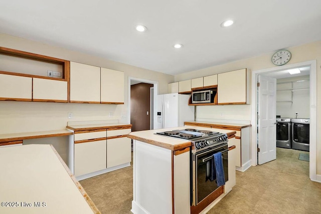 kitchen with electric range oven, a kitchen island, white cabinetry, washer and clothes dryer, and white fridge with ice dispenser