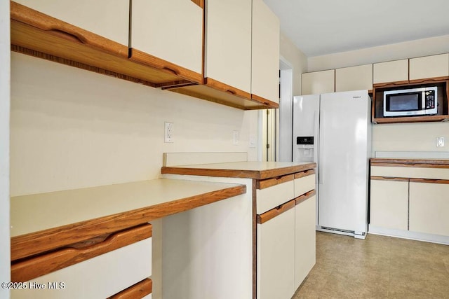 kitchen featuring white cabinets and white refrigerator with ice dispenser