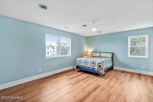 bedroom with ceiling fan, a textured ceiling, and light hardwood / wood-style floors