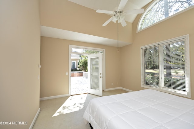 carpeted bedroom with a towering ceiling, access to outside, multiple windows, and ceiling fan