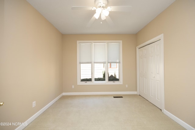 unfurnished bedroom with light carpet, a closet, and ceiling fan