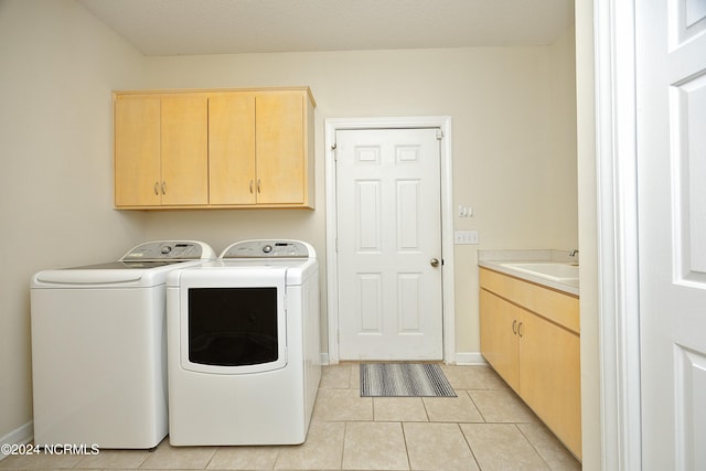 washroom featuring sink, light tile patterned flooring, cabinets, washing machine and clothes dryer, and a textured ceiling