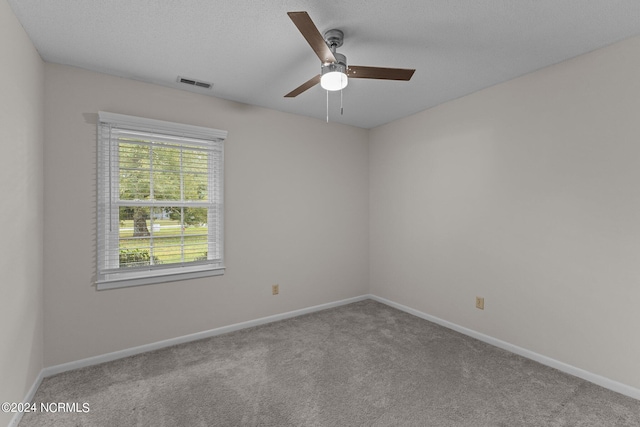 carpeted spare room featuring ceiling fan and a textured ceiling