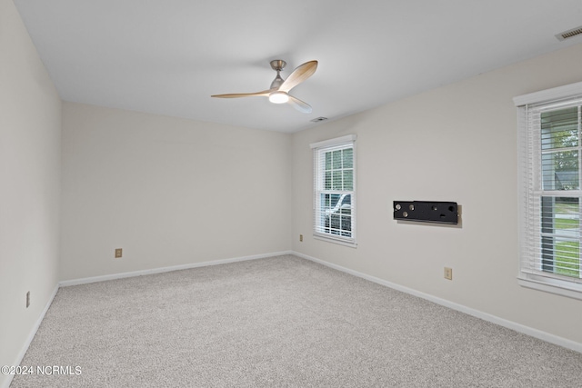 carpeted spare room featuring a healthy amount of sunlight and ceiling fan