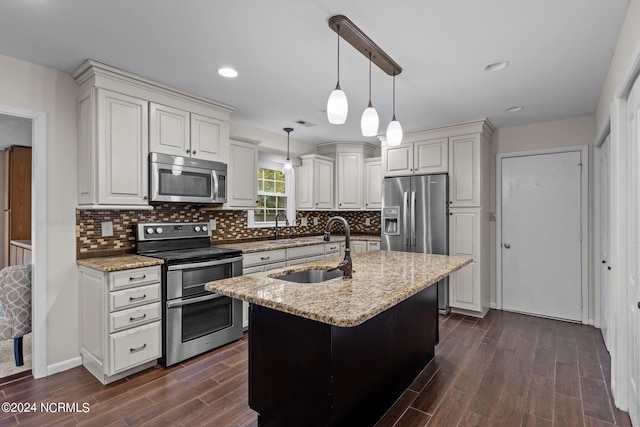 kitchen featuring stainless steel appliances, dark hardwood / wood-style flooring, pendant lighting, and a kitchen island with sink