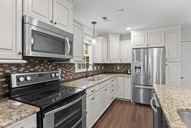 kitchen featuring appliances with stainless steel finishes, white cabinetry, sink, and pendant lighting