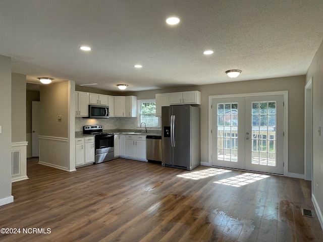 kitchen featuring decorative backsplash, french doors, dark hardwood / wood-style floors, stainless steel appliances, and white cabinets