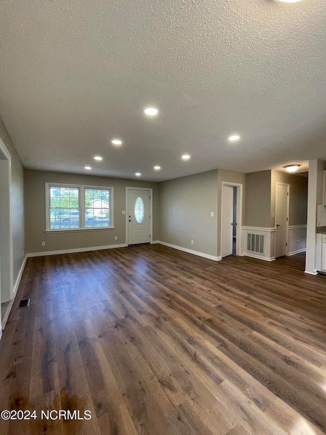 unfurnished living room with dark hardwood / wood-style flooring and a textured ceiling