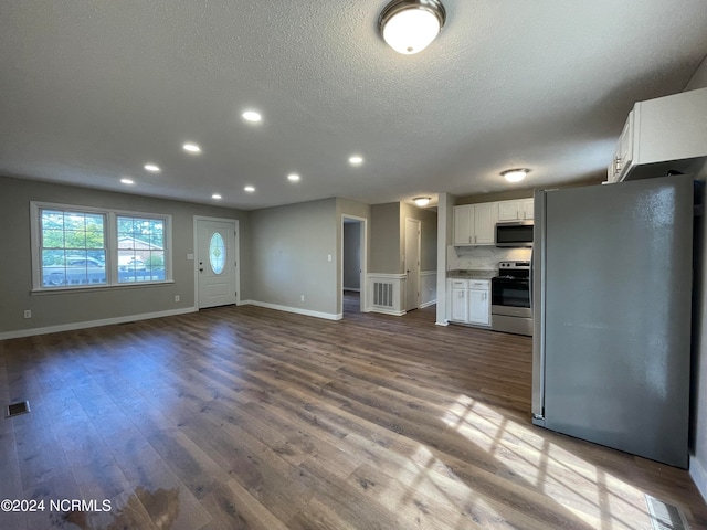 kitchen with wood-type flooring, white cabinetry, stainless steel appliances, and a textured ceiling