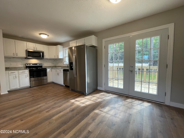 kitchen featuring white cabinets, stainless steel appliances, plenty of natural light, and hardwood / wood-style floors