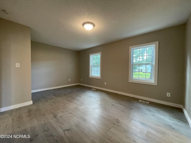 spare room featuring wood-type flooring and a textured ceiling