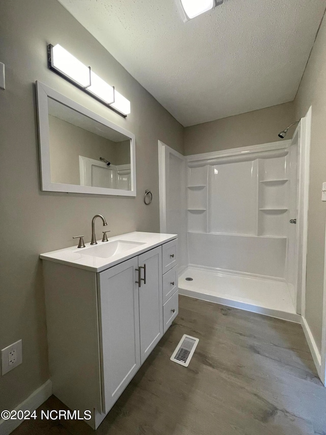 bathroom featuring walk in shower, vanity, a textured ceiling, and hardwood / wood-style flooring