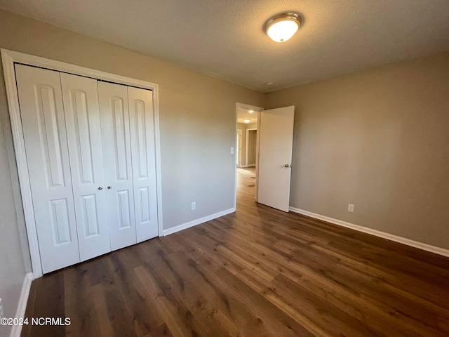 unfurnished bedroom with a textured ceiling, a closet, and dark hardwood / wood-style floors