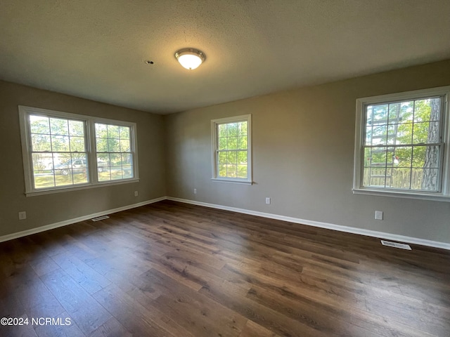 empty room featuring dark hardwood / wood-style flooring and a textured ceiling