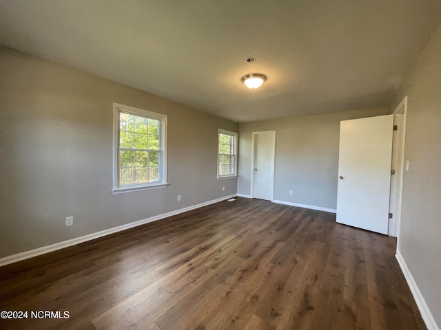 unfurnished room with dark hardwood / wood-style flooring