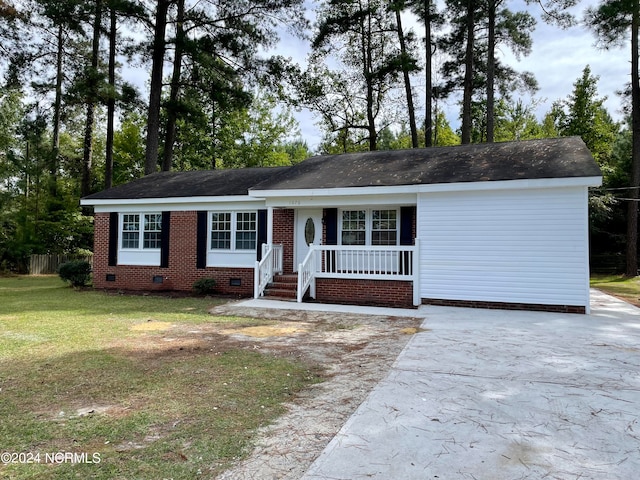 ranch-style home featuring covered porch and a front yard