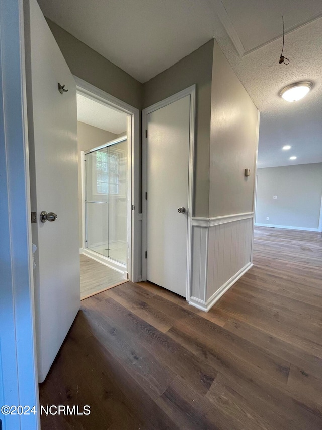 corridor featuring a textured ceiling and dark hardwood / wood-style floors