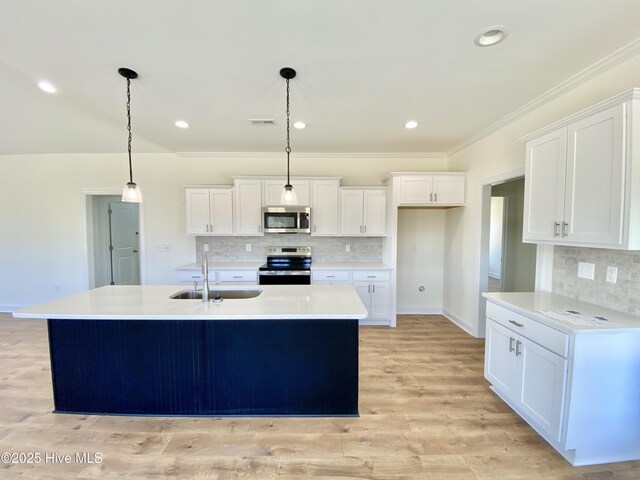 kitchen with pendant lighting, sink, appliances with stainless steel finishes, white cabinets, and a center island with sink