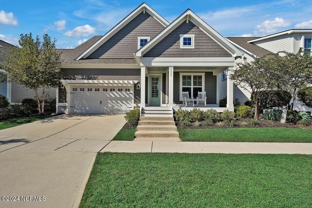 craftsman-style home with a yard, covered porch, and a garage