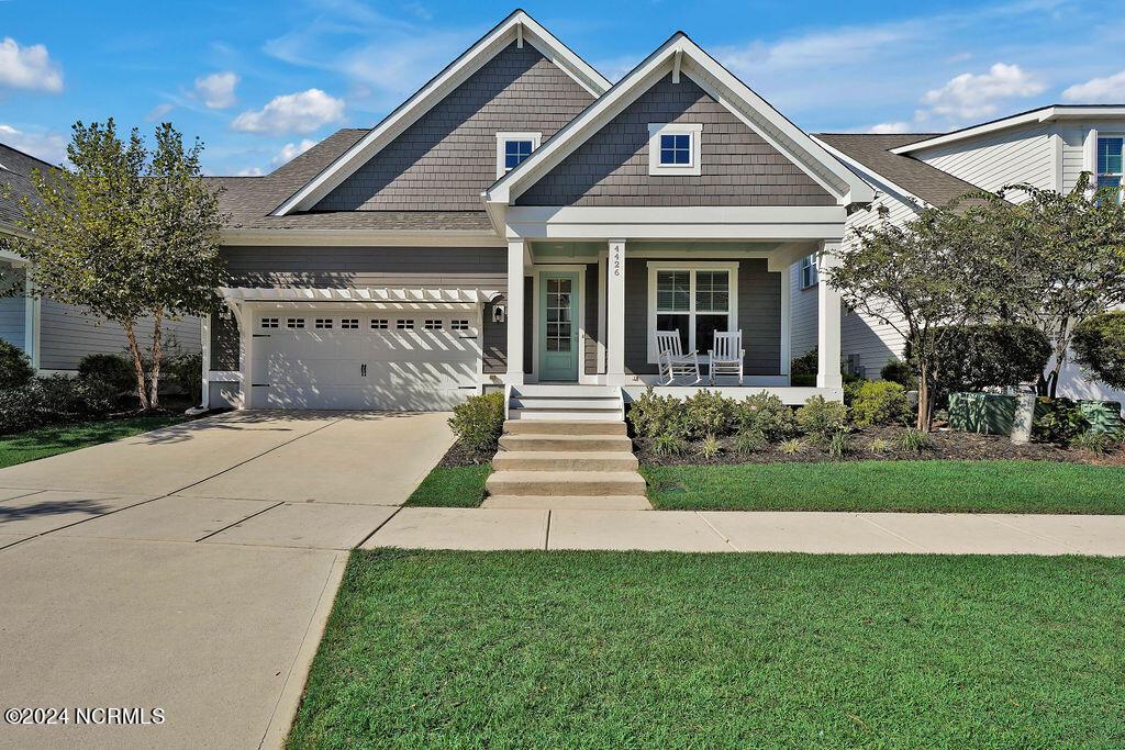 view of front facade featuring a garage, a porch, and a front lawn