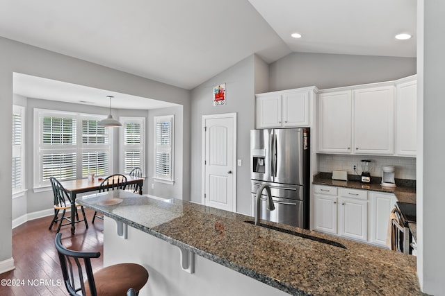 kitchen with stainless steel fridge, dark stone countertops, vaulted ceiling, dark hardwood / wood-style floors, and white cabinets