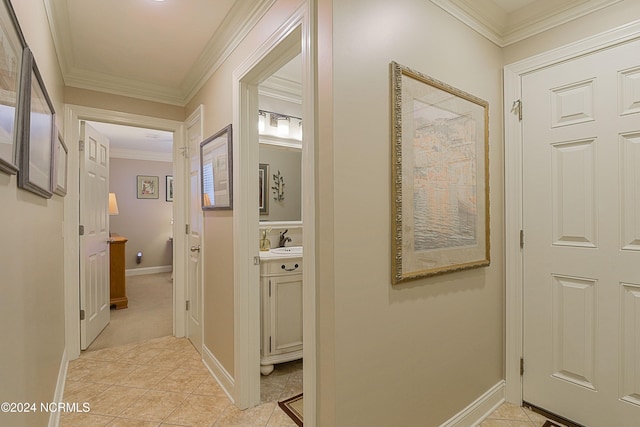 hall with ornamental molding, sink, and light tile patterned floors