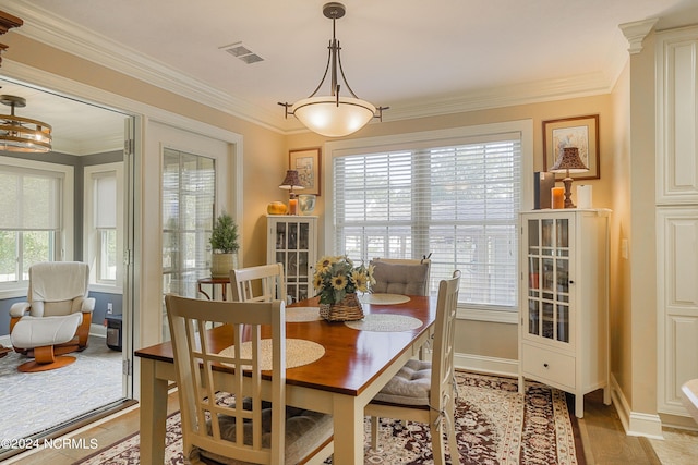 dining space featuring crown molding and light hardwood / wood-style flooring