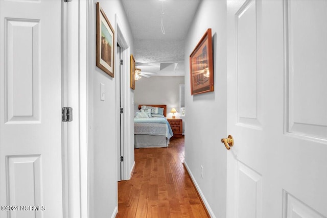 hallway featuring light hardwood / wood-style flooring and a textured ceiling