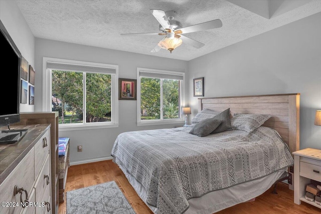 bedroom featuring light hardwood / wood-style flooring, a textured ceiling, and ceiling fan