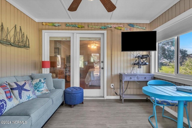 interior space featuring ceiling fan, wood-type flooring, ornamental molding, and wooden walls