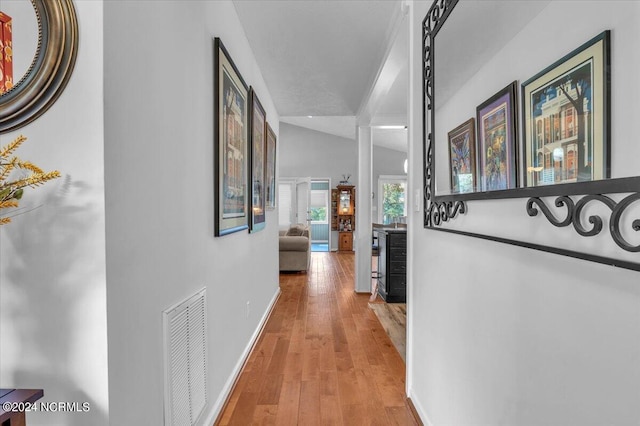 hallway with vaulted ceiling, ornate columns, and light hardwood / wood-style floors