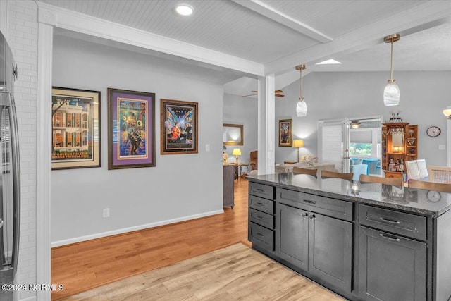 kitchen with light hardwood / wood-style flooring, dark stone countertops, decorative light fixtures, and lofted ceiling