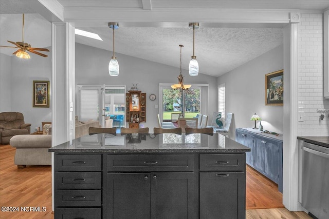 kitchen featuring light hardwood / wood-style flooring, vaulted ceiling, decorative light fixtures, and dishwasher