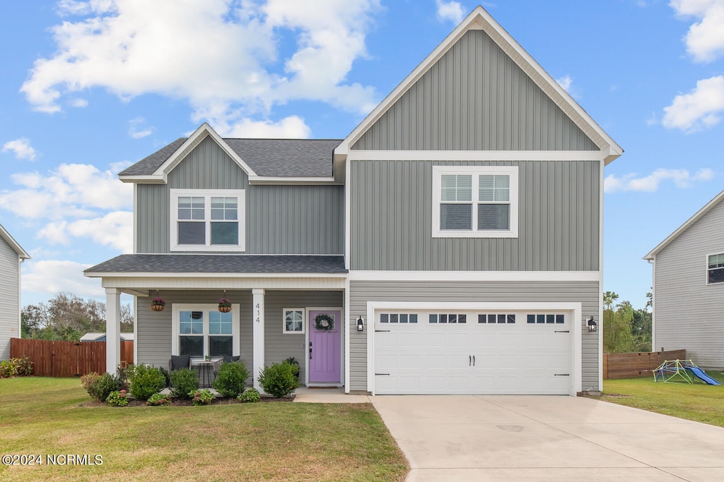 view of front of property with covered porch, a front yard, and a garage