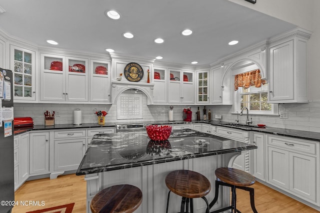 kitchen featuring a kitchen bar, light wood-type flooring, sink, and a kitchen island