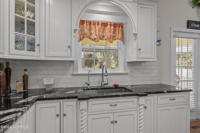 kitchen featuring a healthy amount of sunlight, dark stone counters, and sink