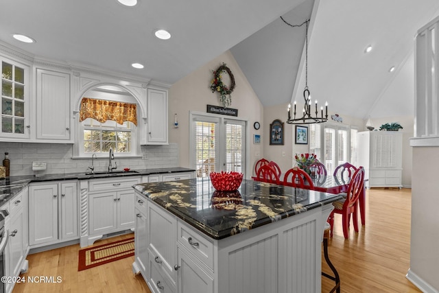 kitchen featuring a kitchen island, sink, light hardwood / wood-style floors, white cabinetry, and vaulted ceiling