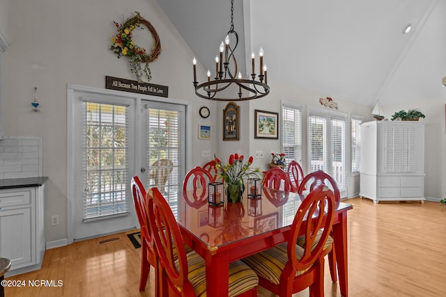 dining area featuring light hardwood / wood-style flooring, a chandelier, and high vaulted ceiling