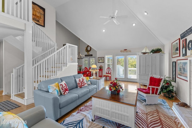 living room with ceiling fan with notable chandelier, high vaulted ceiling, and light hardwood / wood-style floors