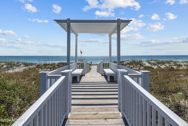 surrounding community featuring a water view, a view of the beach, and a pergola