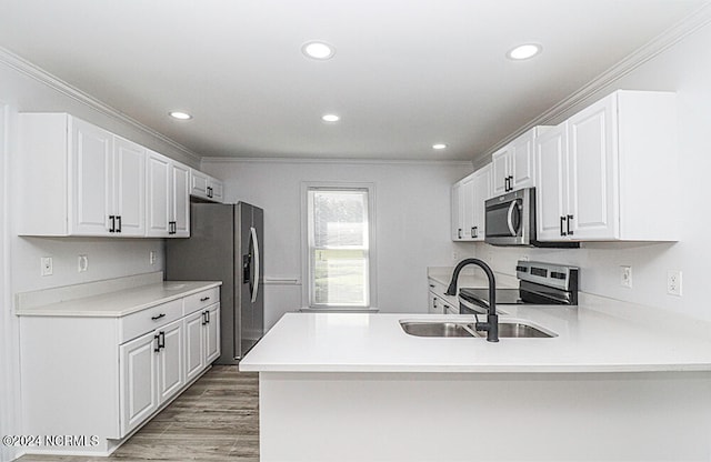 kitchen featuring stainless steel appliances, kitchen peninsula, ornamental molding, and white cabinets