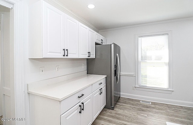 kitchen featuring ornamental molding, light wood-type flooring, stainless steel refrigerator with ice dispenser, and white cabinets