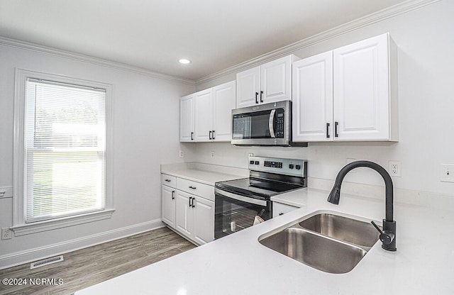 kitchen with stainless steel appliances, wood-type flooring, white cabinets, and sink