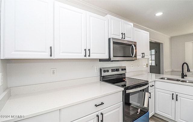 kitchen with appliances with stainless steel finishes, crown molding, white cabinetry, and sink