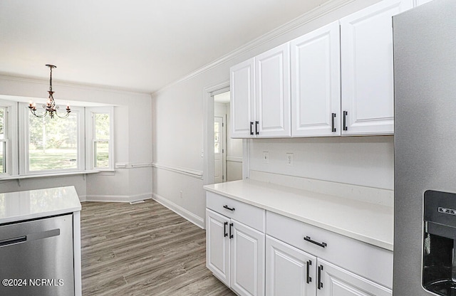 kitchen featuring an inviting chandelier, hardwood / wood-style floors, stainless steel appliances, ornamental molding, and white cabinets