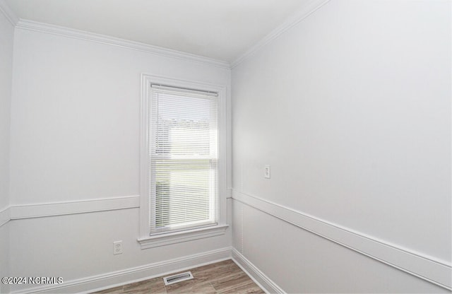 empty room featuring wood-type flooring and crown molding