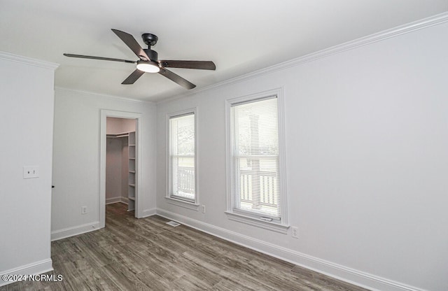 empty room with ceiling fan, ornamental molding, and dark wood-type flooring