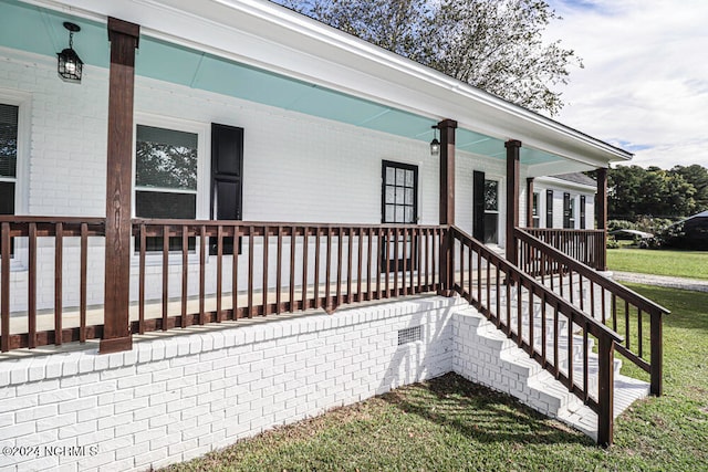 view of exterior entry featuring a yard and covered porch