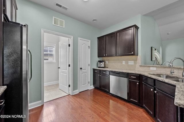 kitchen with sink, tasteful backsplash, wood-type flooring, stainless steel appliances, and light stone countertops