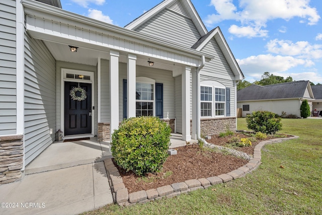 view of exterior entry with a porch and a lawn